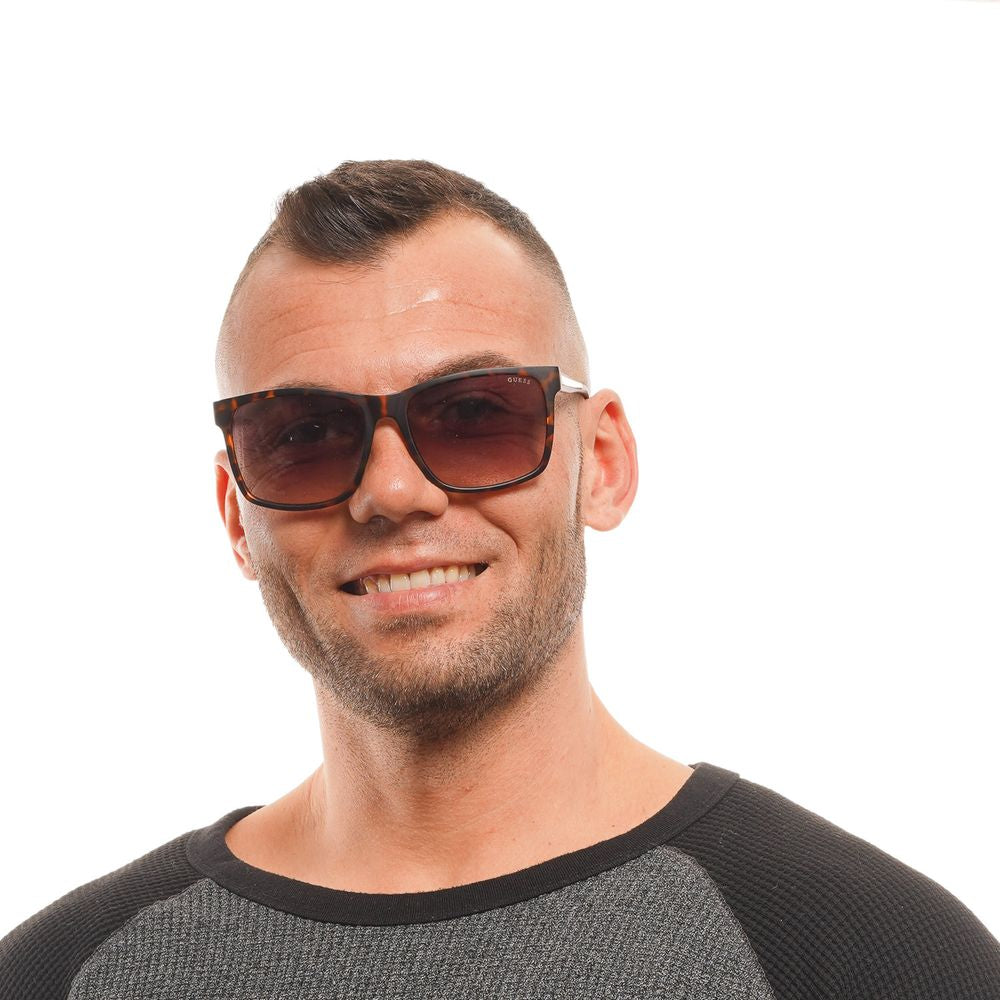 Man wearing Guess brown men's sunglasses with square gradient lenses and full-rim plastic frame, offering 100% UVA & UVB protection.