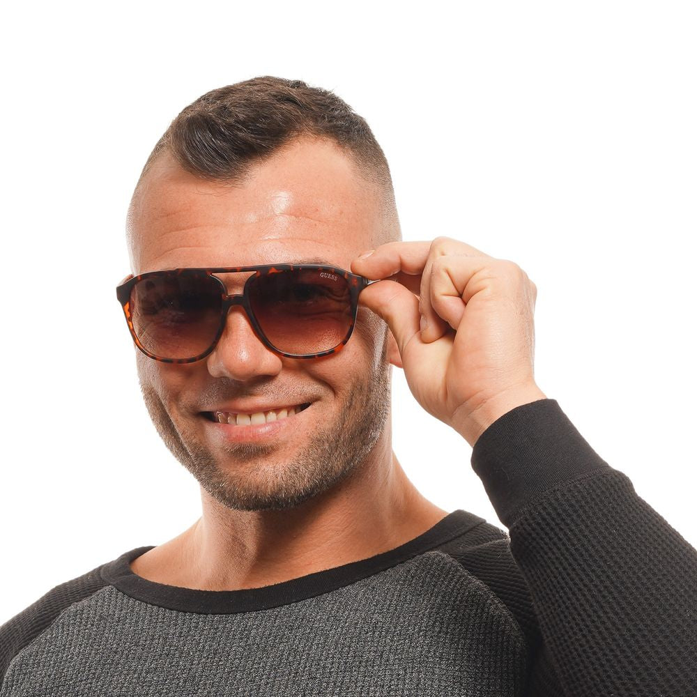 Man wearing Guess brown aviator sunglasses with full-rim style and gradient brown lenses.