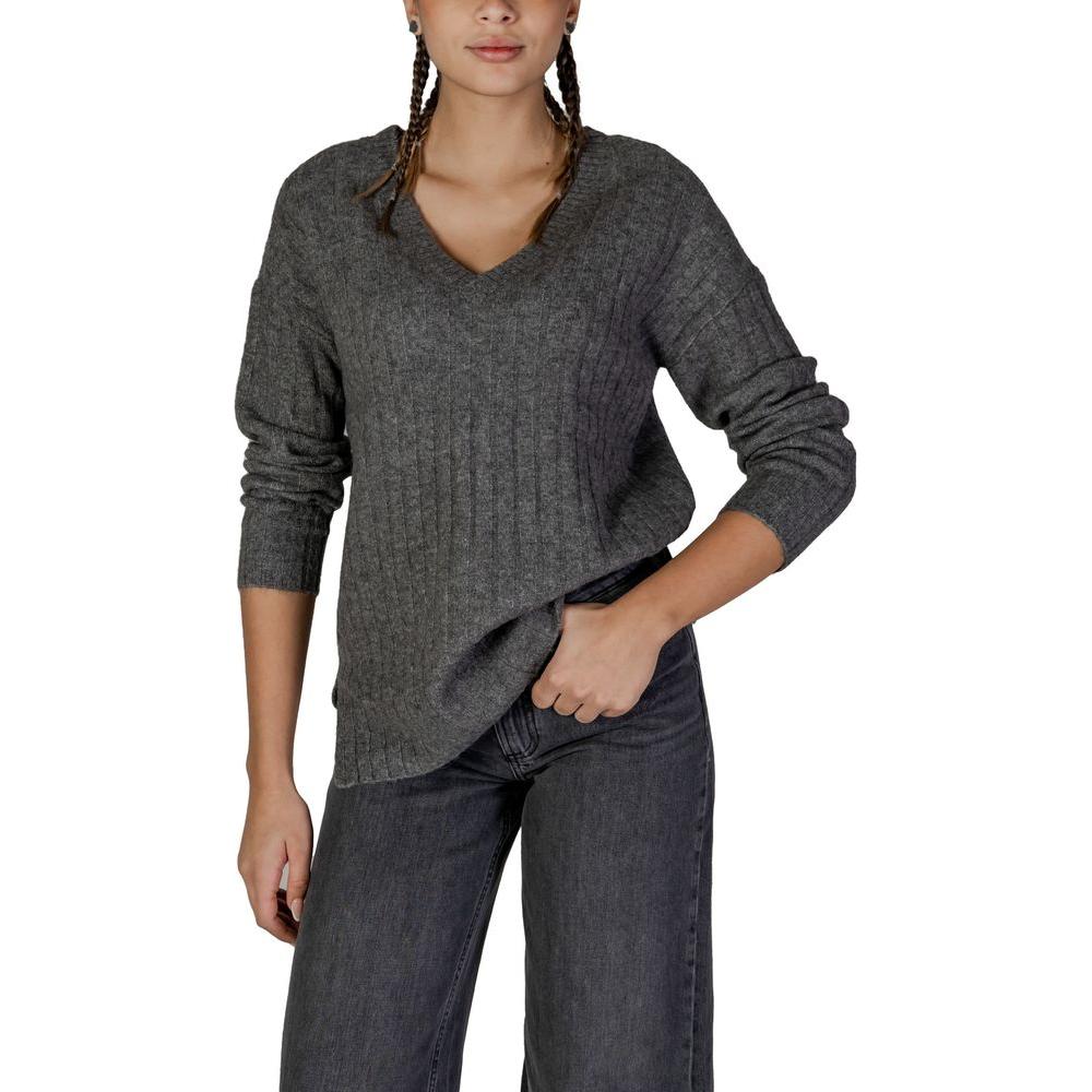 Woman wearing Vila Clothes gray acrylic fall/winter sweater with v-neck, paired with jeans.