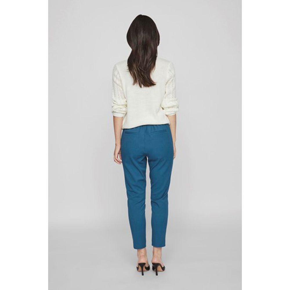 Woman wearing Vila Clothes blue polyester cigarette pants, fall/winter collection, back view, standing against a gray background.