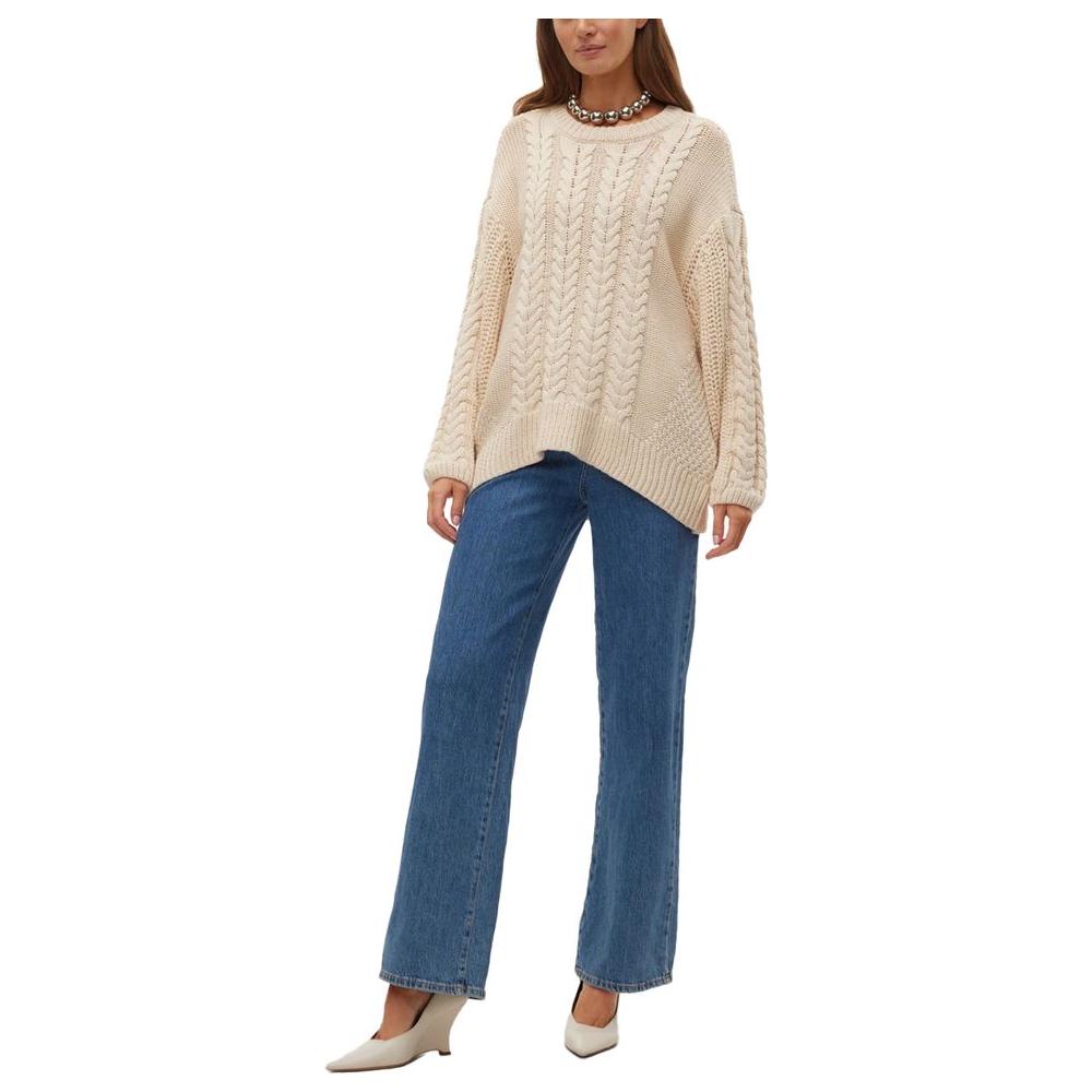 Vero Moda beige cotton sweater for women, featuring a fall/winter knitwear design, worn with blue jeans and white heels.