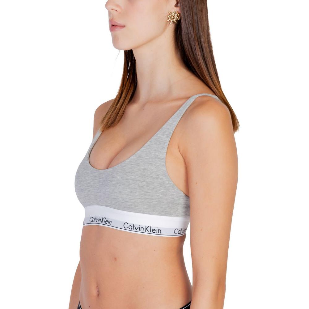 Woman wearing Calvin Klein gray cotton bralette, minimalist design, comfortable fit, lightly lined, for everyday wear.