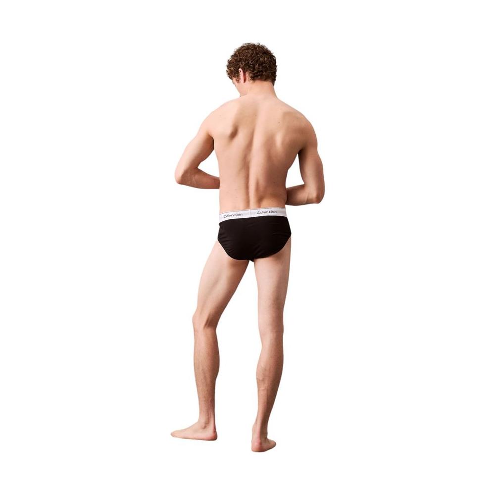 Man wearing Calvin Klein black hip brief underwear with logo waistband, showing back view.