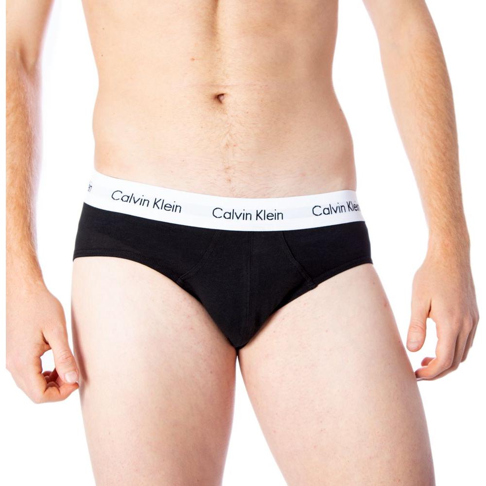 Man wearing black Calvin Klein hip briefs with logo waistband, showcasing comfort and style.