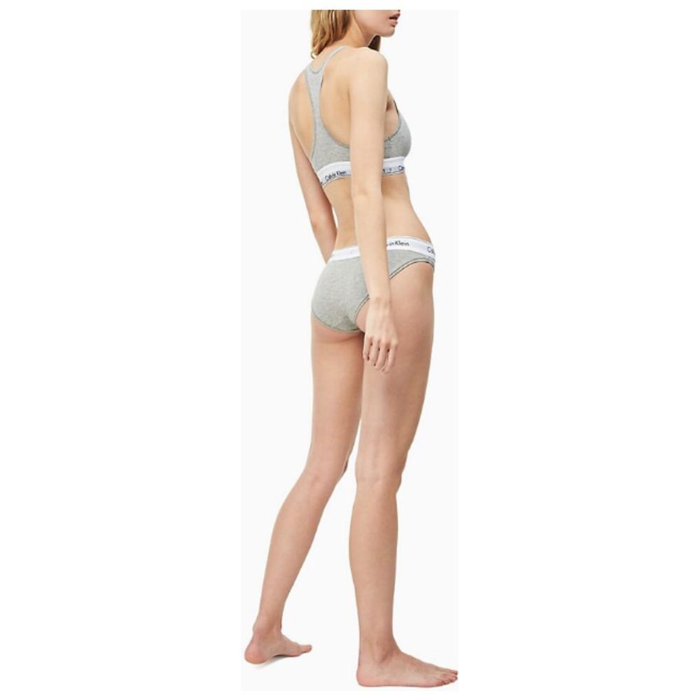 Model wearing Calvin Klein gray cotton underwear bikini briefs with logo waistband, showcasing minimalist and comfortable design.