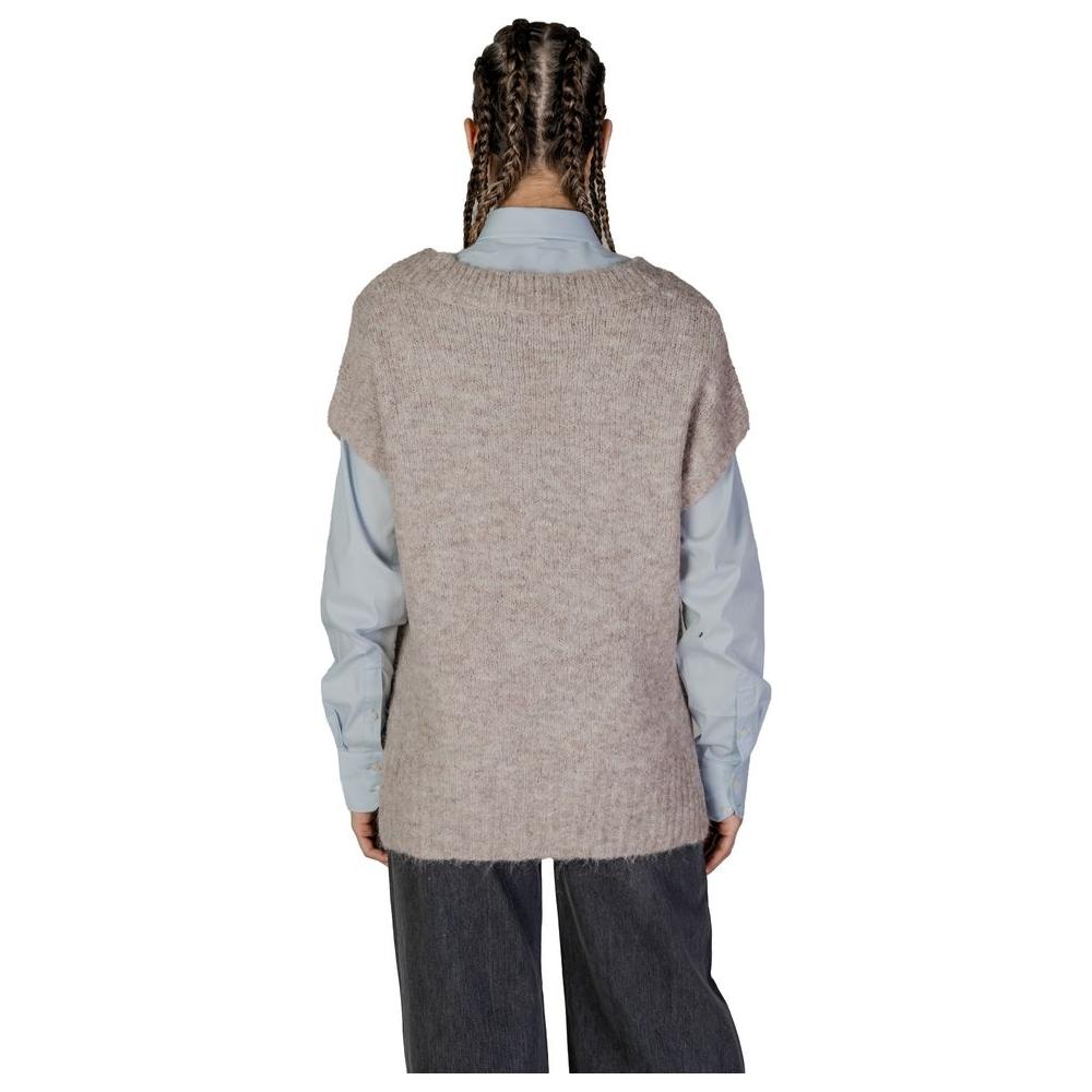 Back view of woman wearing Vero Moda beige recycled polyester sweater over light blue shirt, part of fall/winter collection.