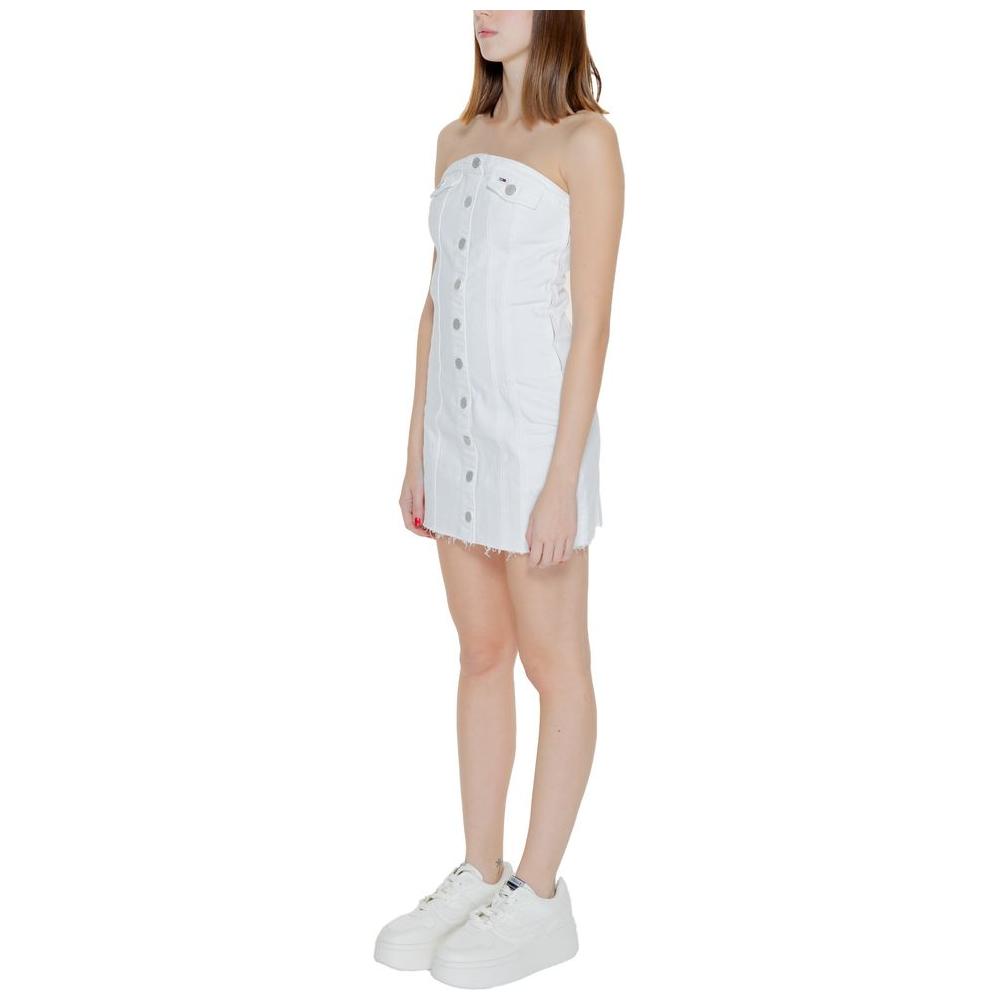 Woman wearing Tommy Hilfiger white recycled cotton strapless dress, spring/summer collection, with button details and casual sneakers.