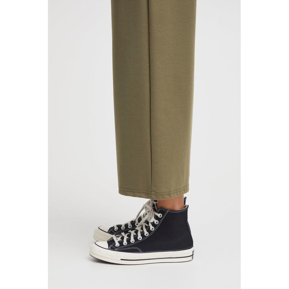 Close-up of ICHI women's green bootcut recycled polyester pants with black sneakers, featuring fall/winter sustainable fashion.
