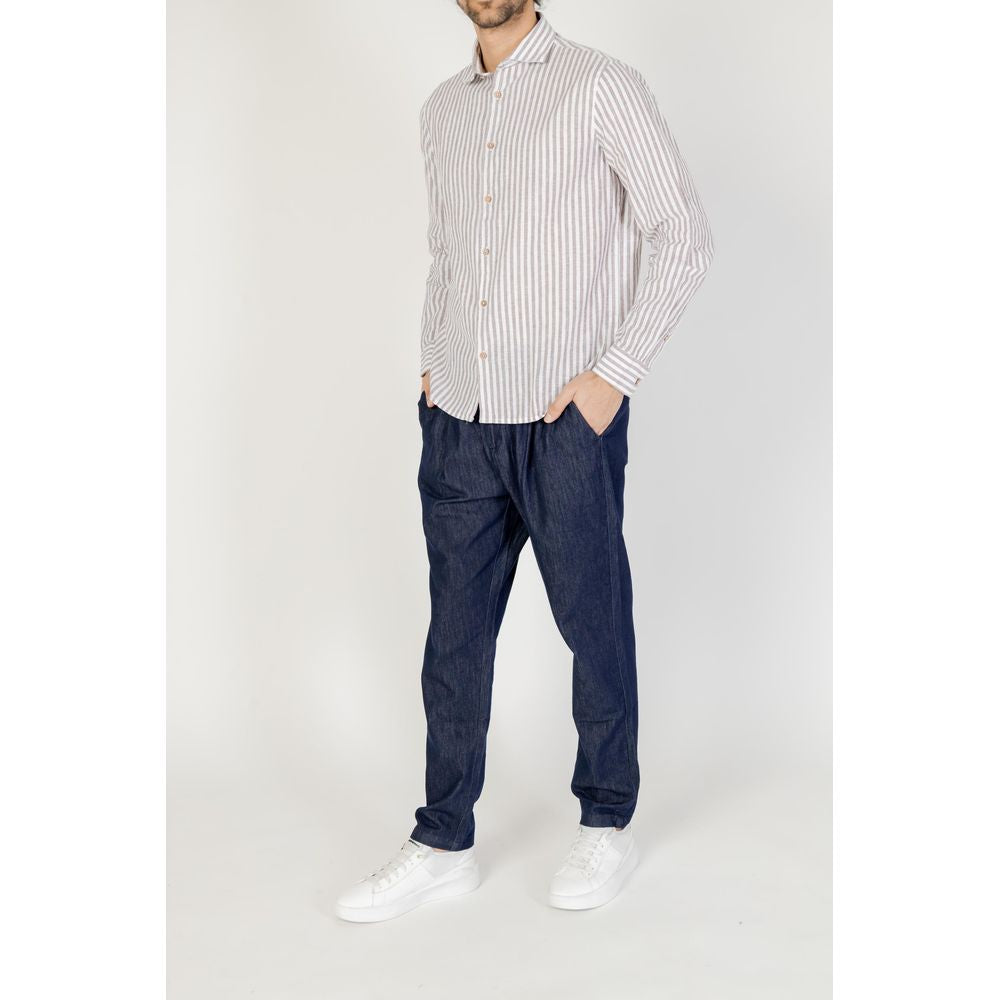 Man wearing a Hamaki-Ho brown linen shirt, part of the men's long-sleeved Spring/Summer collection, paired with dark jeans and white sneakers.