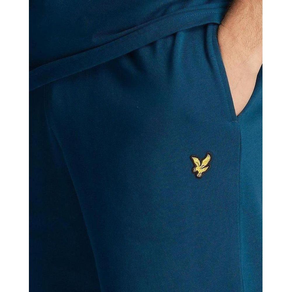 Close-up of blue Lyle & Scott shorts with gold emblem. Comfortable cotton material shown in a stylish fall/winter design.