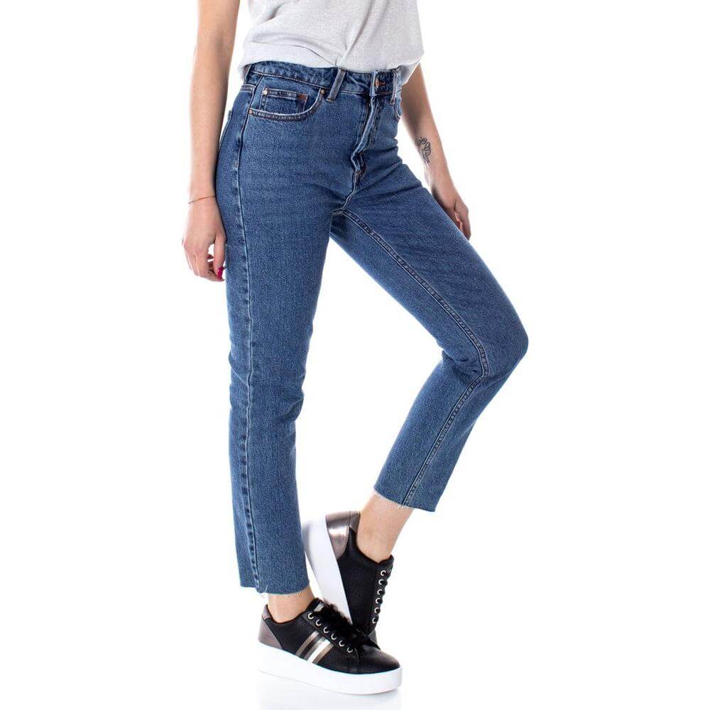 Woman wearing high-waisted blue cotton mom jeans with ankle-cut design, paired with sneakers, showcasing a casual stylish look.