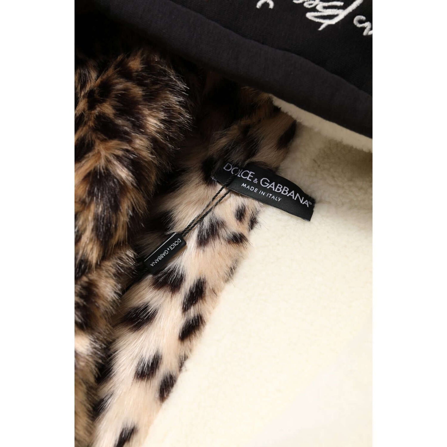 Dolce & Gabbana label inside black hooded jacket with leopard print lining, showcasing luxury fashion and Italian craftsmanship.