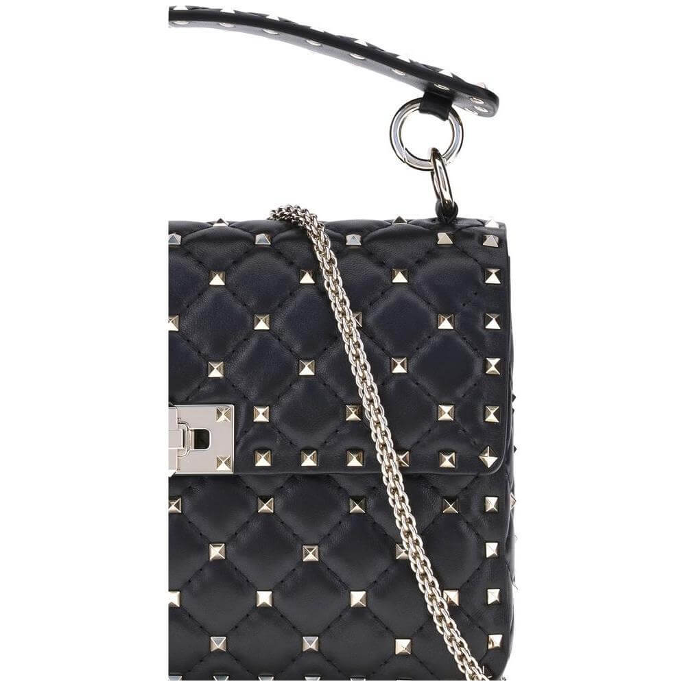 Close-up of Valentino Garavani Rockstud Spike shoulder bag in black quilted leather with gold-tone studs and chain details.