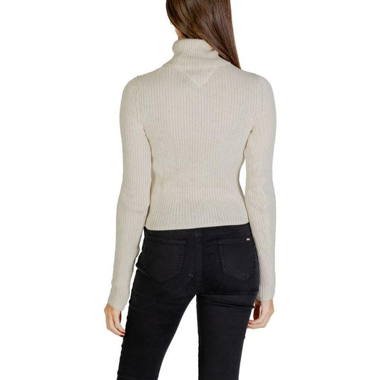 Back view of woman wearing Tommy Hilfiger beige recycled polyester sweater, part of the fall/winter knitwear collection.