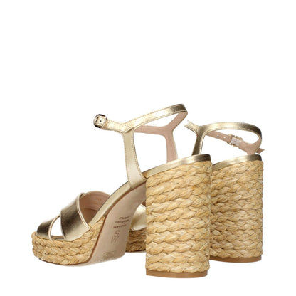 Stuart Weitzman Gold Leather Platform Sandals with metallic effect and natural woven heel detail, perfect for elegant summer wear.