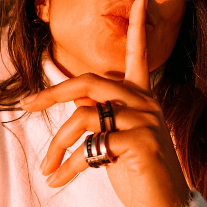 Woman wearing rings from AN JEWELS JEWELRY Mod. AR.R2NS02BK-9 collection, hand gesture with index finger on lips.