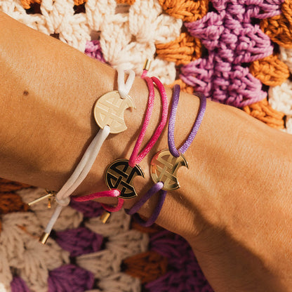 Three colorful AN JEWELS JEWELRY Mod. AV.BGLBGGPK bracelets on wrist against crochet background.