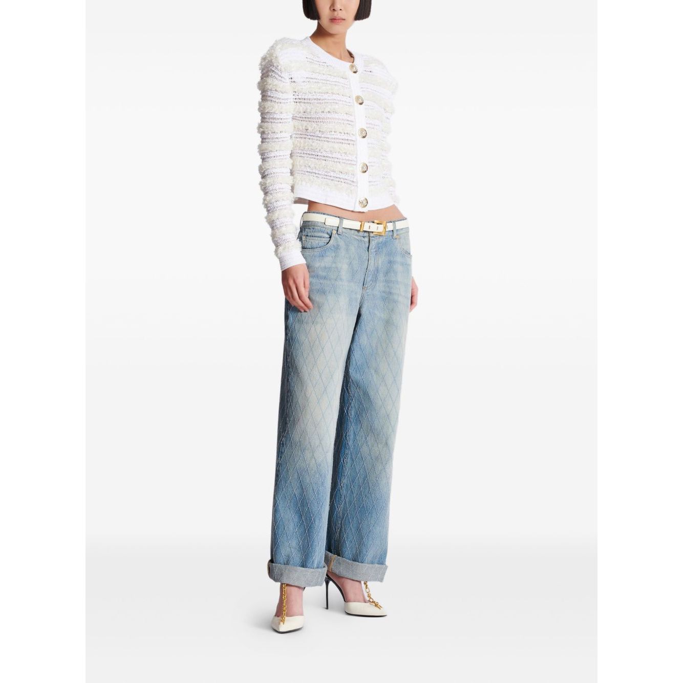 Model wearing Balmain Long-sleeved tweed-effect knit cardigan with white button fastening, paired with blue jeans and heels.