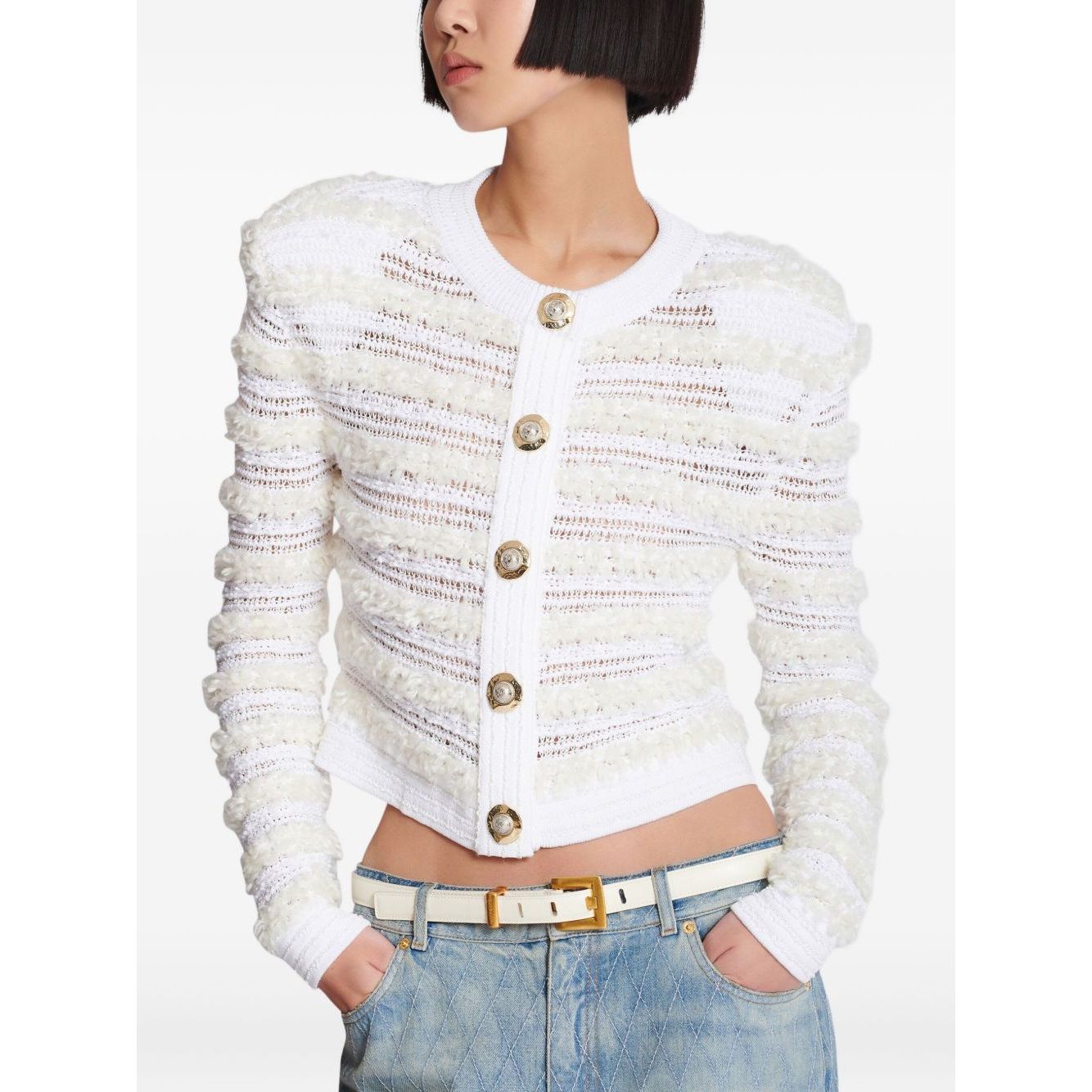 Model wearing Balmain Long-sleeved tweed-effect knit cardigan, white with front button fastening and ribbed trim, paired with jeans.