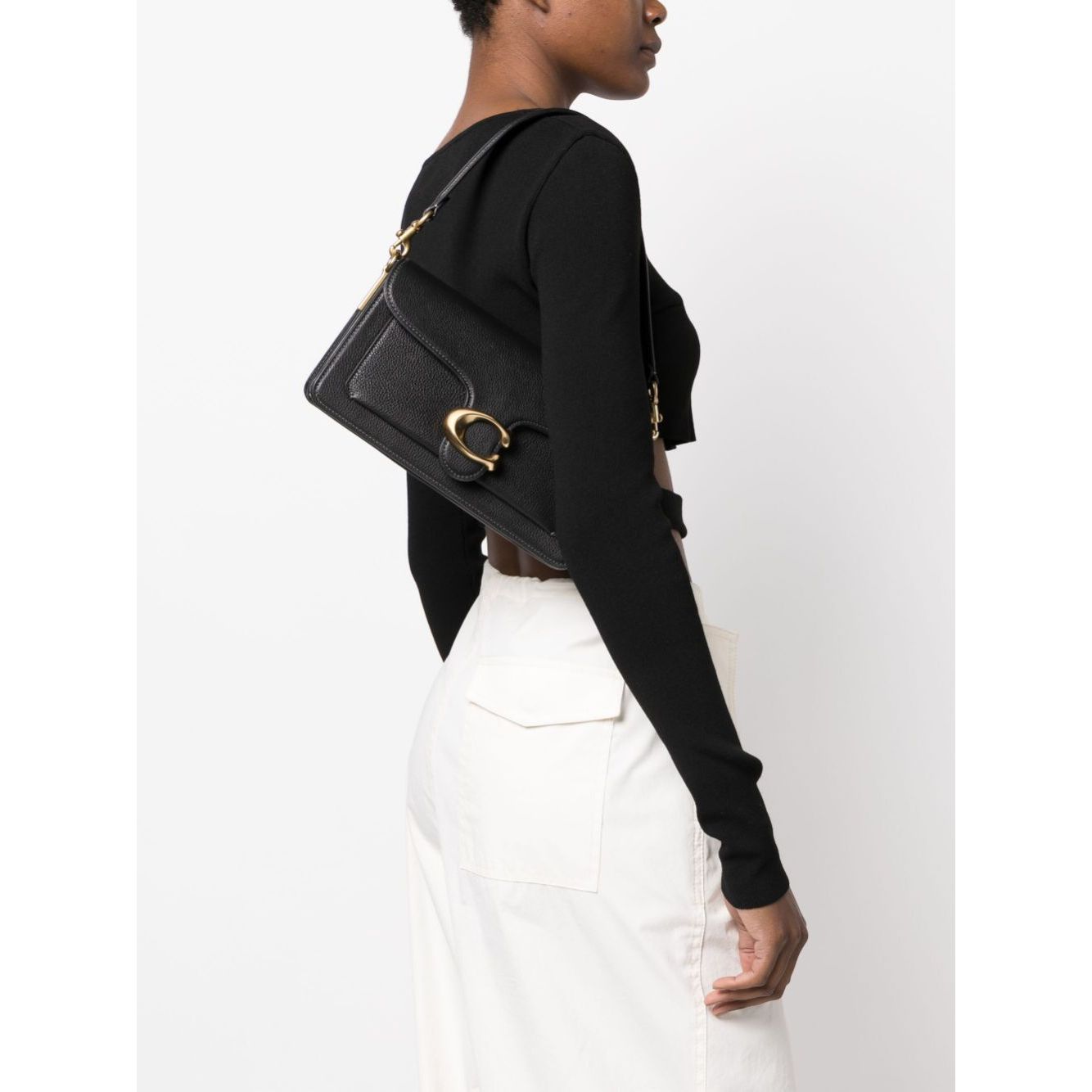 Woman wearing Coach Tabby 26 leather shoulder bag with adjustable strap and gold hardware