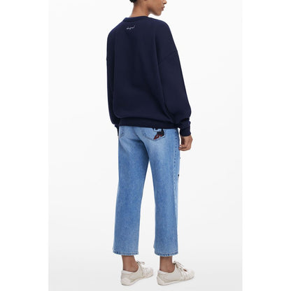 Rear view of model wearing Desigual Blue Cotton Women Sweater with Mickey print, paired with jeans and sneakers, showcasing stylish back design.