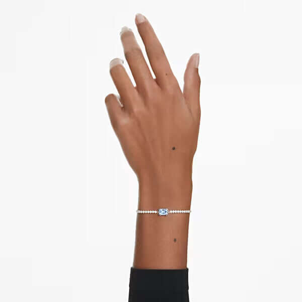 Elegant hand model showcasing a delicate silver bracelet with a sparkling crystal centerpiece on a white background.